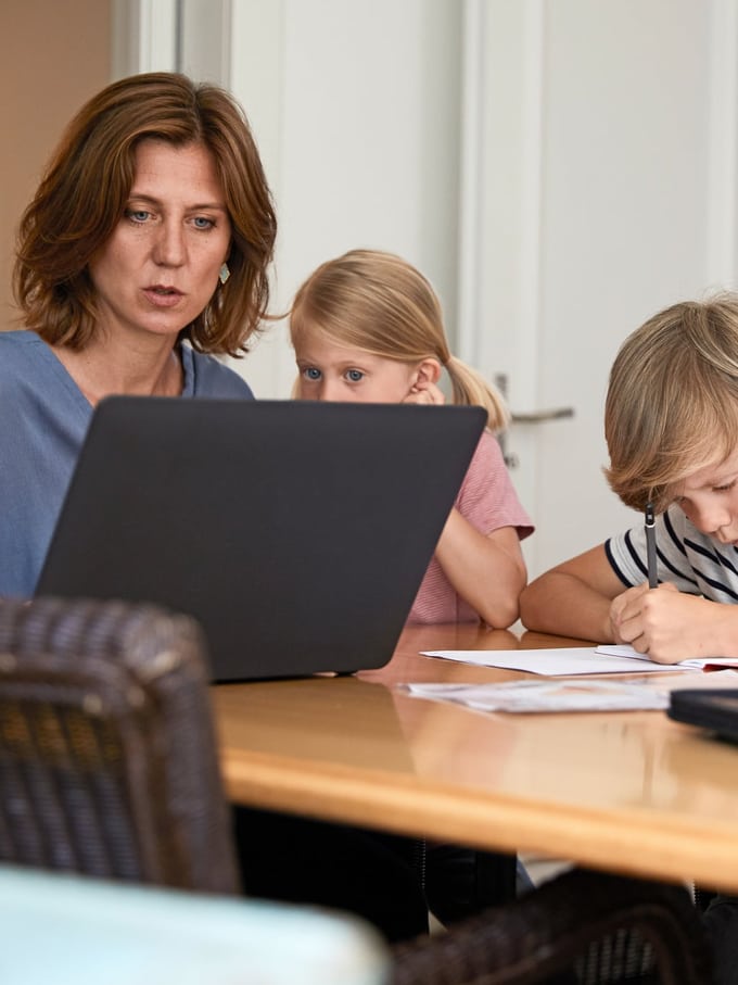 Maman est assise sur son ordinateur portable avec deux enfants.