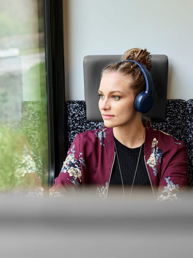 Une femme est dans le train avec des écouteurs.