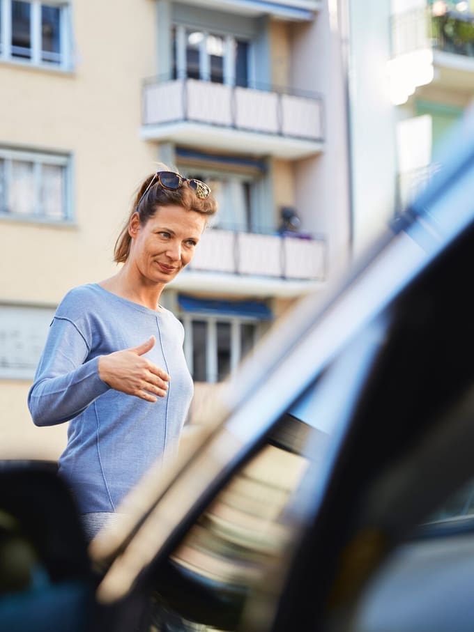 Eine Frau vor einem parkierten Auto