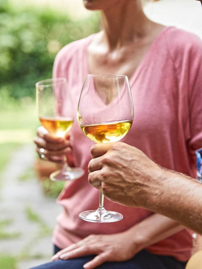 Symbolbild für Alkohol am Steuer in der Schweiz: Zwei Personen stossen mit Gläsern draussen an.