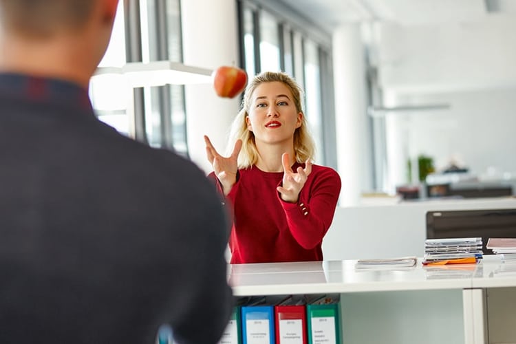 Eine Frau wirft einem Mann einen Apfel zu.