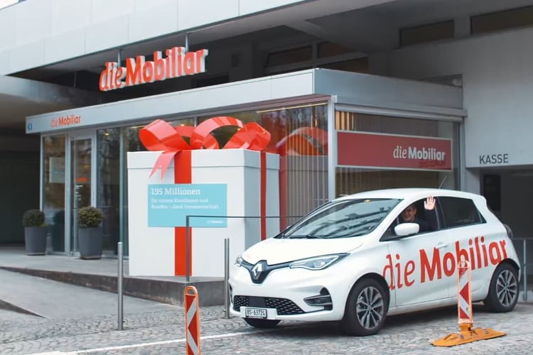 Ein Mobiliar-Fahrzeug steht vor einer Mobiliar Filiale.