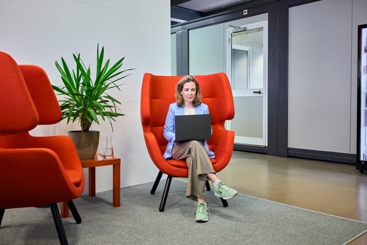 Femme dans un fauteuil avec un ordinateur portable au travail
