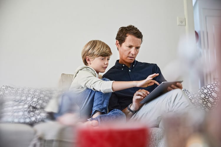 Un père et son fils font du shopping en ligne sur le canapé
