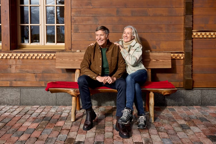 Älteres Paar sitzt auf einer Bank und schaut positiv in die Ferne als Symbolbild für Patientenverfügung.