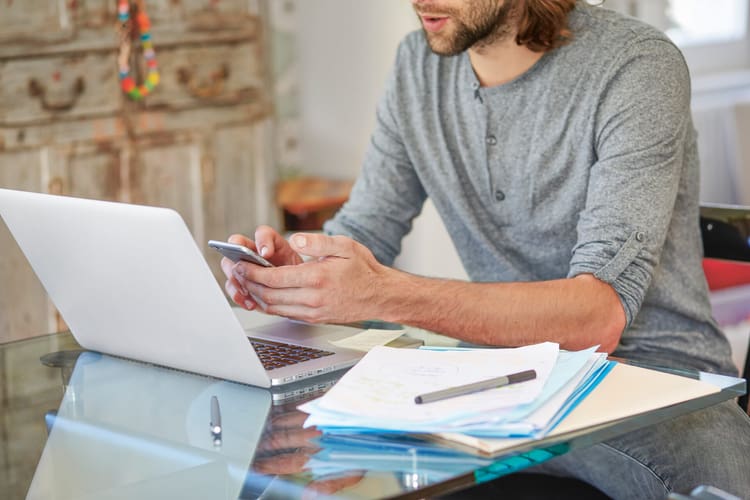 Un homme travaille avec un laptop et un smartphone.