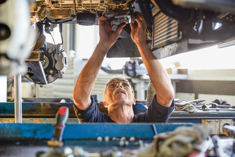 Un homme dans un garage sous une voiture