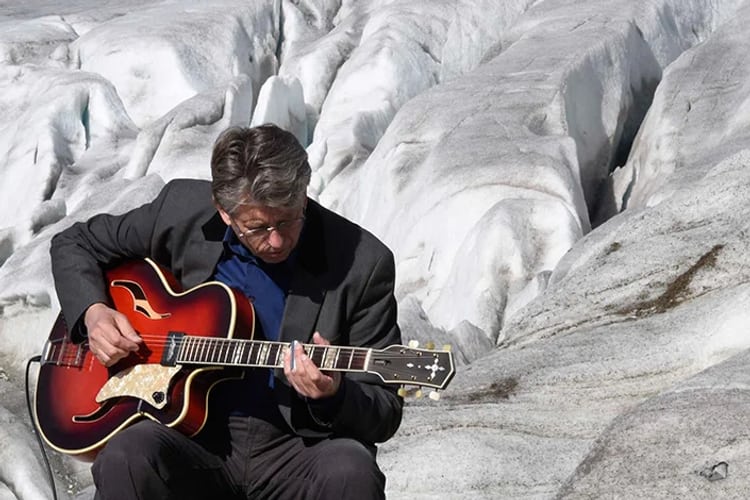 L’uomo è seduto sul ghiacciaio e suona la chitarra