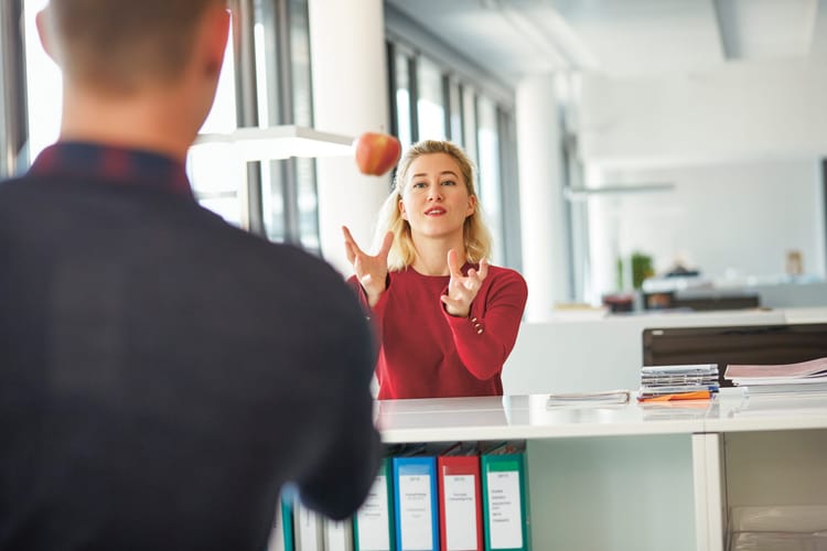 Femme attrapant une pomme au bureau