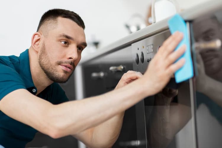 Mann putzt einen Backofen.
