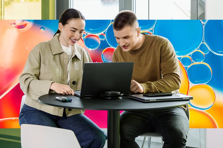 Zwei junge Personen schauen in ein Notebook