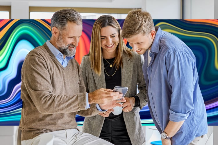 Drei Personen schauen auf ein Smartphone