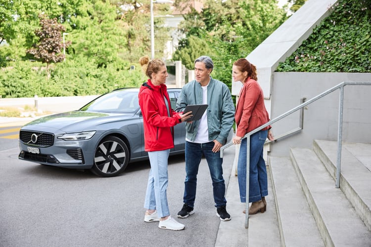 Consulente assicurativa a colloquio con i clienti davanti a un’auto