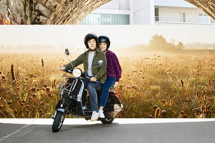 Deux jeunes femmes sur un scooter, casque sur la tête, s’apprêtent à démarrer. 