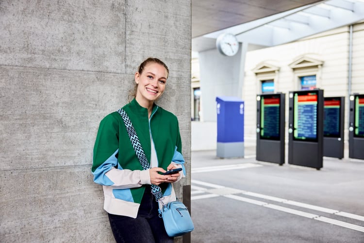 Eine junge Frau mit Handy in einem Bahnhof