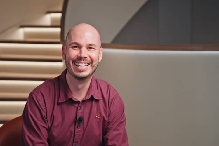 Mitarbeitender sitzt vor einer Treppe