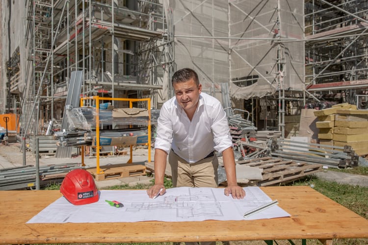 Tomislav Soldo, Inhaber des Geschäfts Eltec Elektro, stützt sich mit den Händen auf einen Tisch, der auf einer Baustelle steht. 