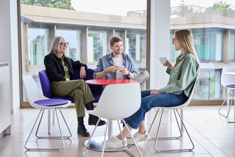 Drei Personen sitzen glücklich zusammen am Tisch