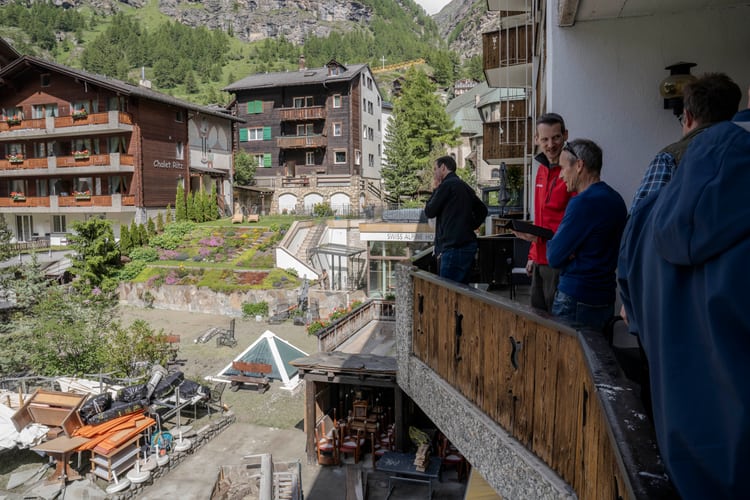 Delle persone in piedi su un balcone guardano i danni provocati dalle inondazioni di Zermatt nel 2024.