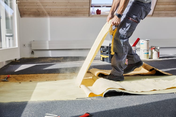 Arbeiter entfernt alten Teppichboden beim Umbau eines Wohnzimmers