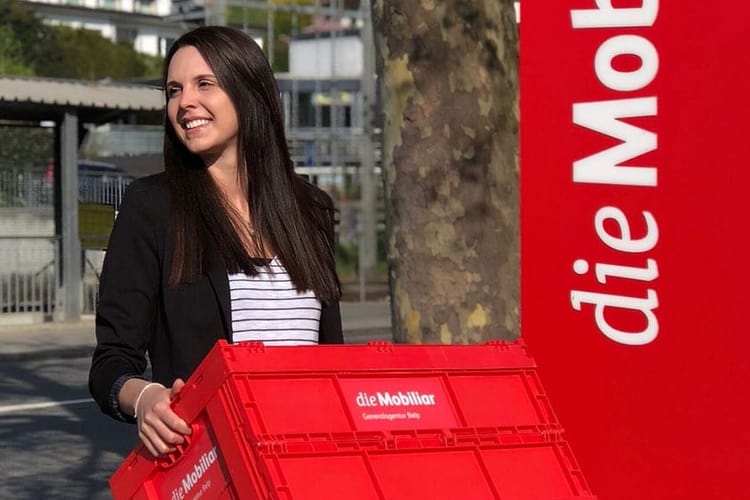 Eine Frau trägt eine Umzugskiste der Mobiliar.