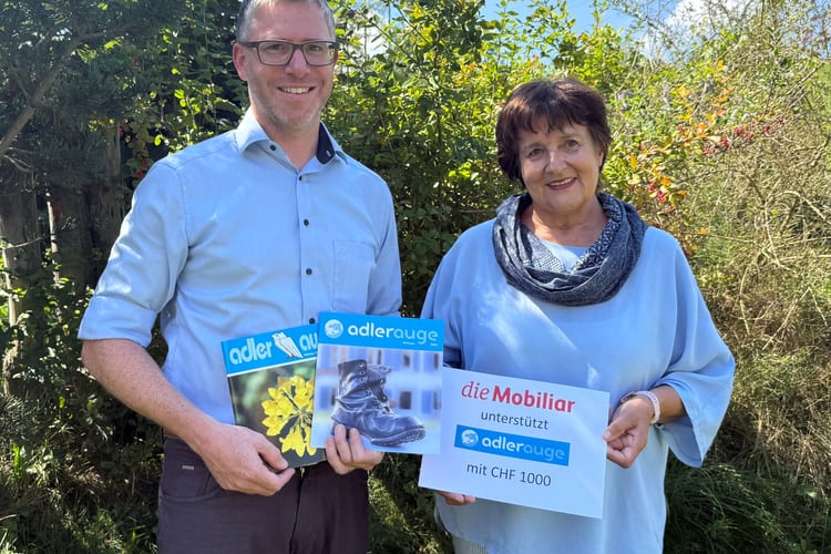 2 Personen halten einen Mobiliar-Check und 2 Adlerauge Magazine.