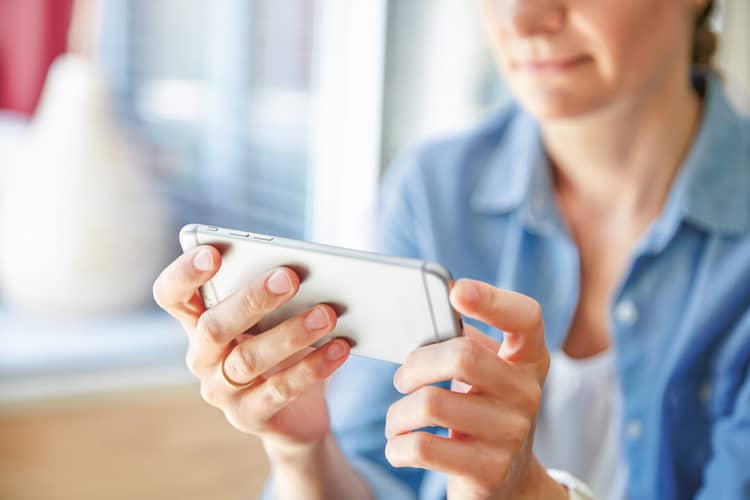 Une femme utilise un smartphone argenté.