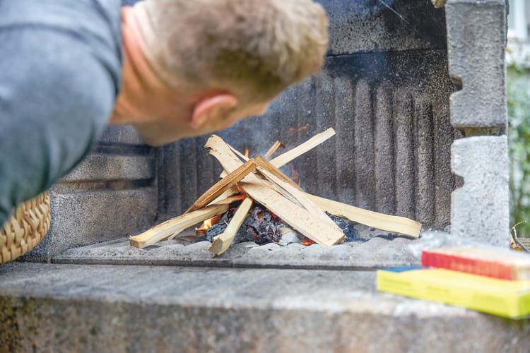 Immagine che simboleggia il disturbo olfattivo: alcuni pezzi di legno sono disposti uno sopra l'altro in modo incrociato e un uomo sta per dargli fuoco.