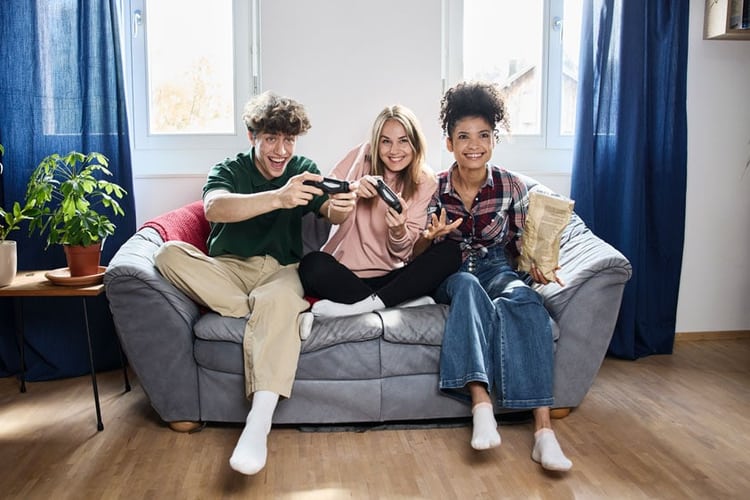 3 giovani giocano sul divano videogiochi