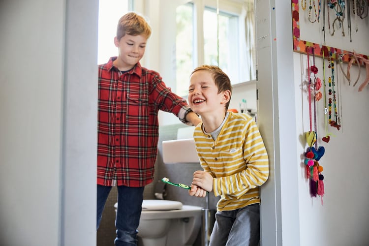 Deux garçons en train de se brosser les dents ou d’essayer de le faire.