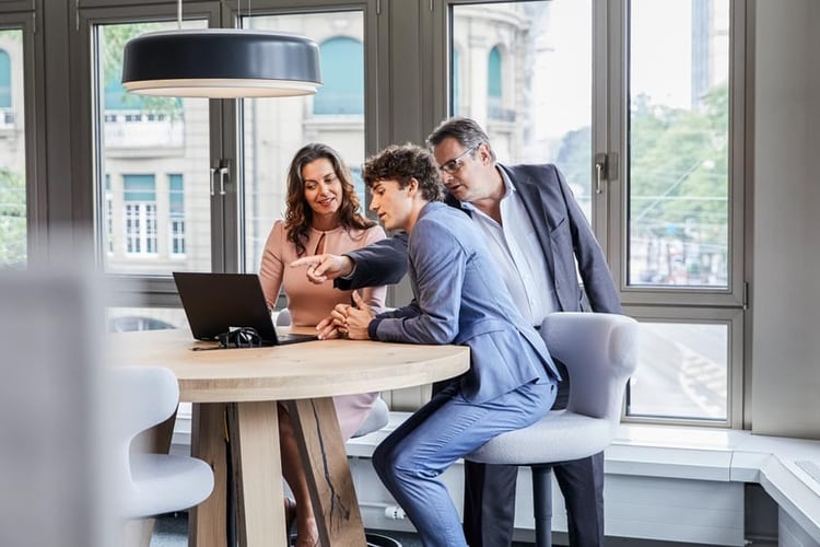 Trois personnes discutent de quelque chose sur un laptop