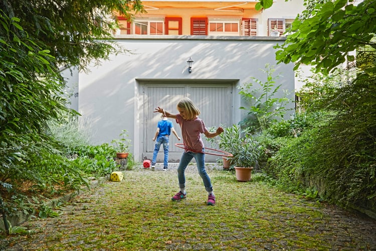 Deux enfants jouent dans une entrée de cour.