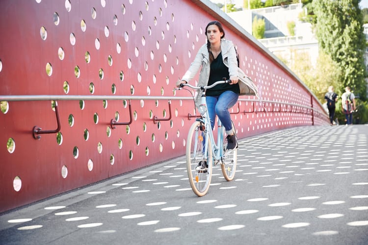Eine Frau am Velofahren auf einer Brücke in der Stadt