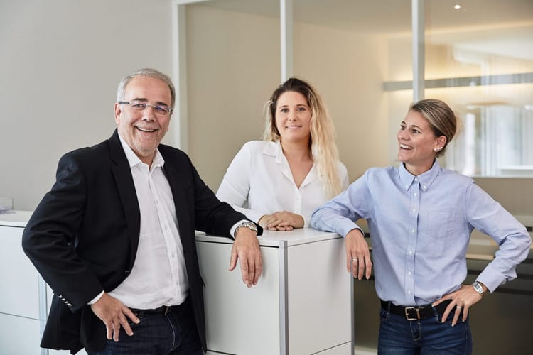 Ein älterer Herr und zwei Damen in einem Büro am reden