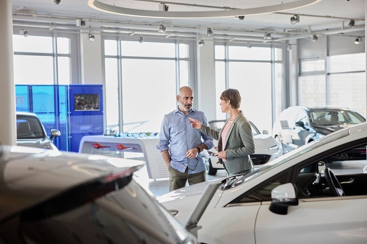 Un homme et une femme sont en discussion dans la halle d’exposition d’un concessionnaire automobile. 