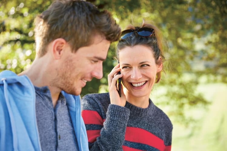 Zwei Personen im Park und die Frau telefoniert.