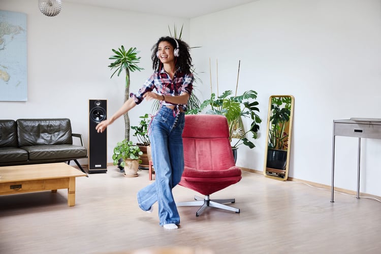 Eine Frau tanzt mit Kopfhörer in ihrer Wohnung.