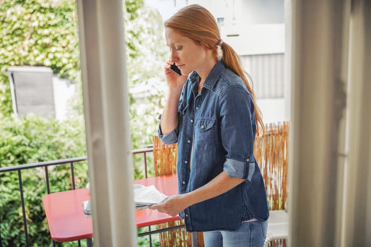 Quishing oder QR-Code-Phishing: Frau mit Zeitung und Handy (Sinnbild)