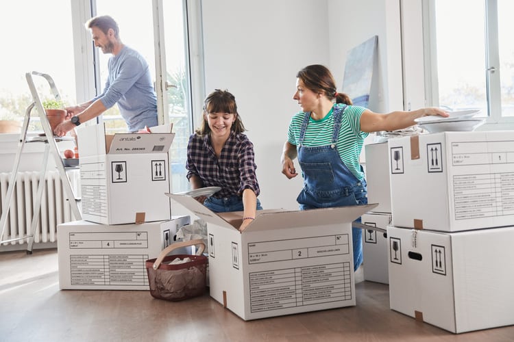 Drei Personen packen Umzugskartons aus