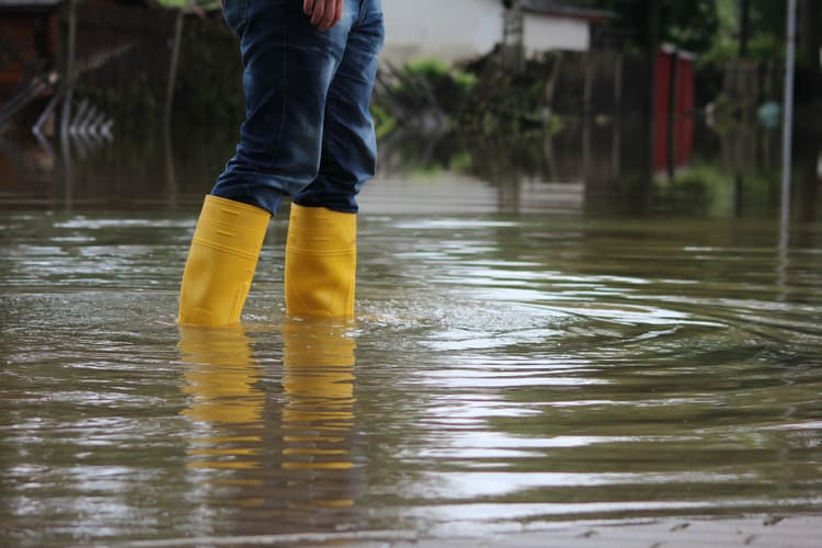 Person läuft mit Gummistiefel durch Hochwasser