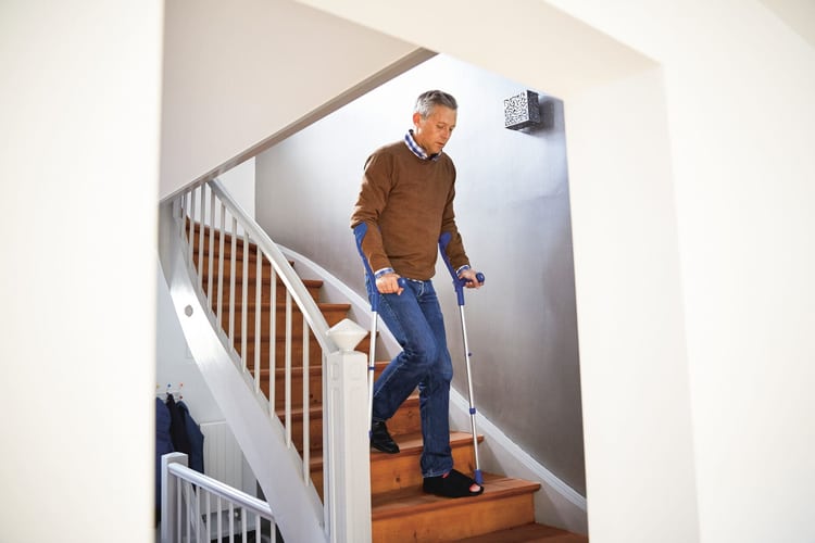 Un homme avec des béquilles descend un escalier.