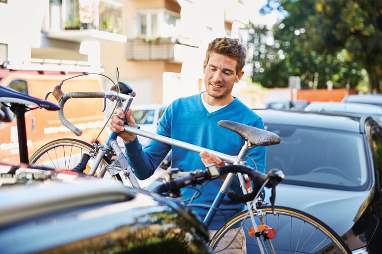 Mann befestigt Velo auf Veloständer am Auto  
