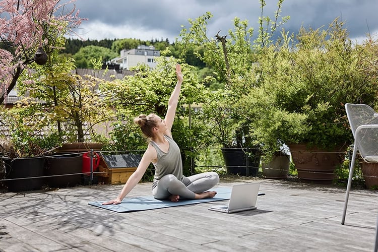 Jeune femme fait du yoga sur une terrasse.