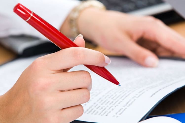 Eine Person mit Dossier und Kugelschreiber in den Händen