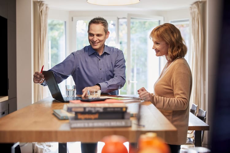 Ein Mann und eine Frau an einem Stehtisch mit einem Laptop
