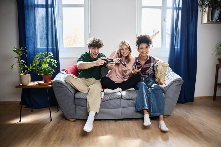 3 Jugendliche sitzen auf einem Sofa und gamen
