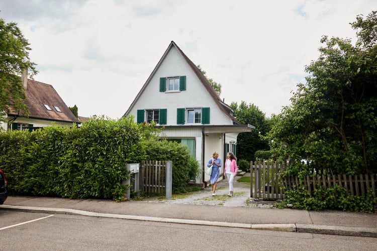 Haus mit zwei Personen im Vorgarten