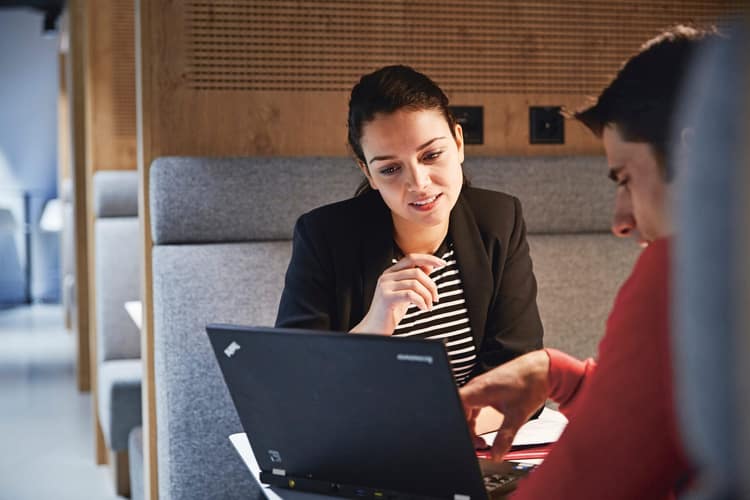 Frau und Mann besprechen etwas und blicken gemeinsam in einen Laptopbildschirm
