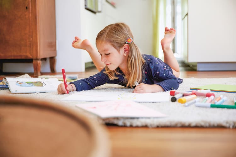 Una bambina dipinge sul tappeto