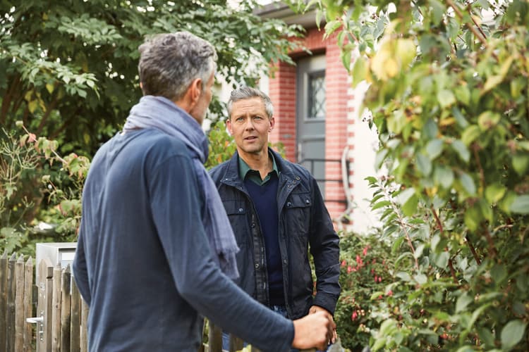 Zwei Männer unterhalten sich draussen vor einem Haus. Symbolbild für Nachbarschaftsstreit. 